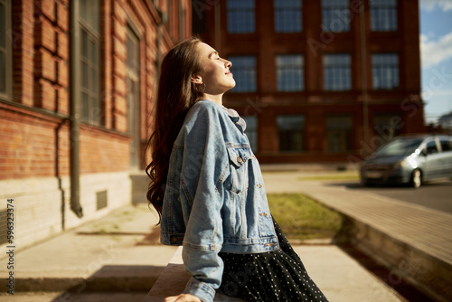 Murais de parede Side view outdoor image of gorgeous student girl with closed eyes in denim outfi