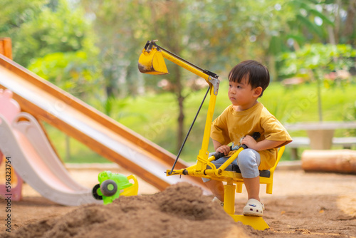 Kid baby boy todler playing construction truck toy diging sand in playground