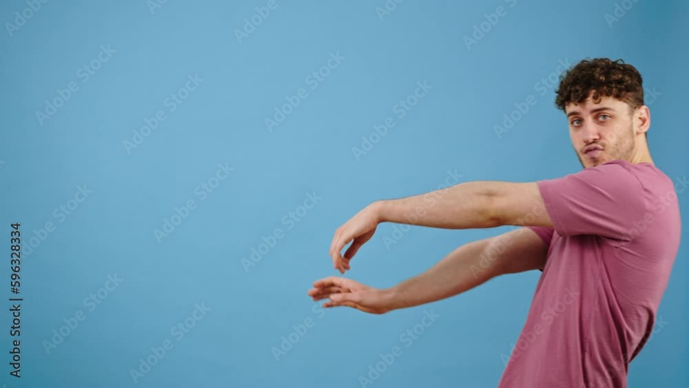 Handsome man appears over blue background, performing freestyle dance and wainks looking at camera Handsome man appears over blue background, performing freestyle dance and wainks looking at camera