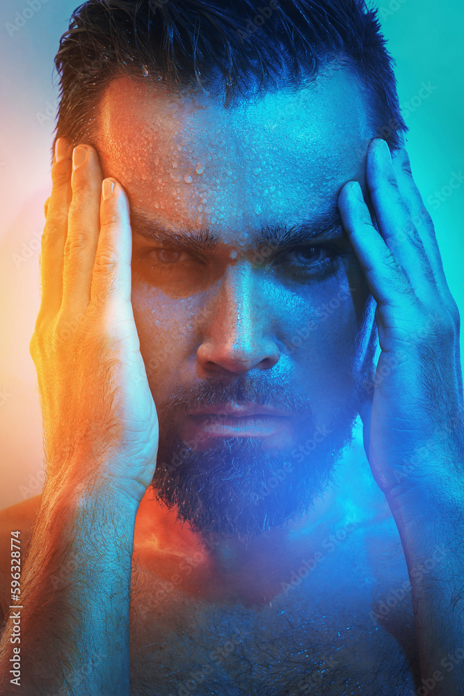 Fototapeta premium Handsome young man with wet face in blue and orange light