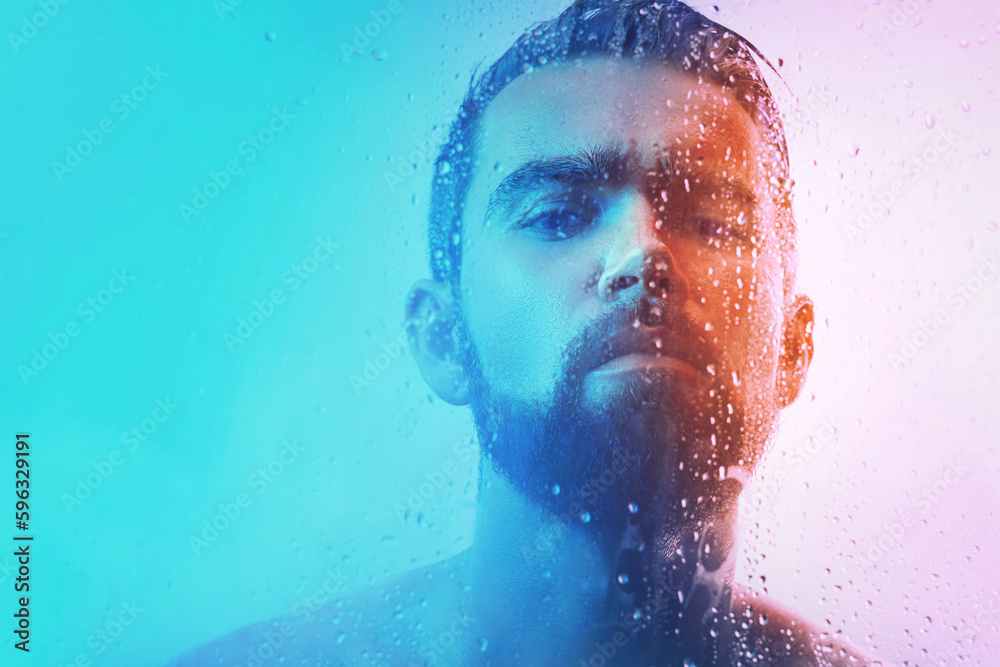 Portrait of handsome young man captured through wet glass in blue and orange light