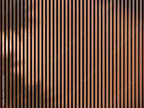Acoustic fluted wood panel, cloth black back material. Plant leaf shadow falling onto panel.