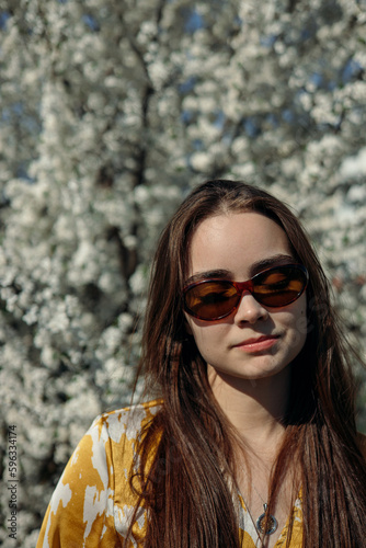 Portrait of woman with closed eyes enjoying sunny day in spring park with blooming trees 