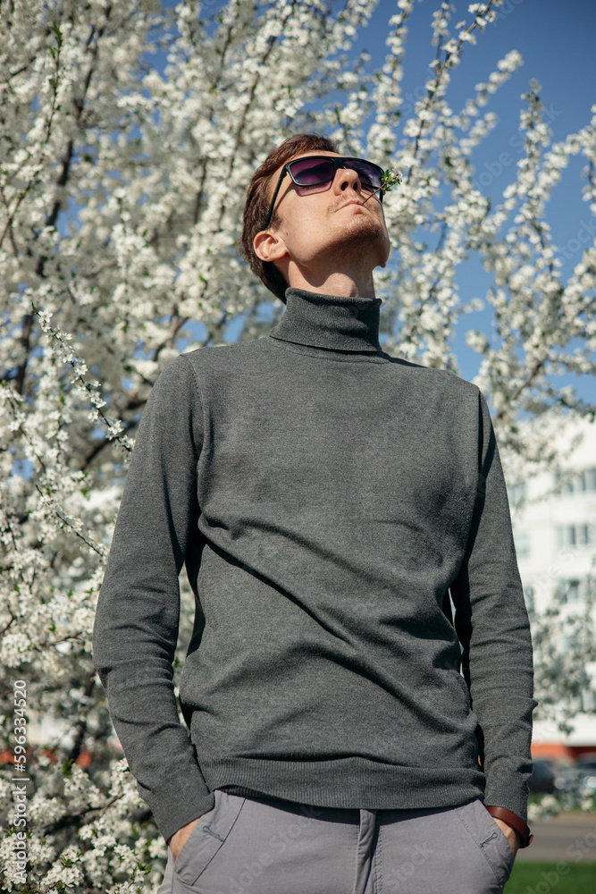 Daydreaming man enjoying spring in garden with blooming trees in white flowers Daydreaming man enjoying spring in garden with blooming trees in white flowers