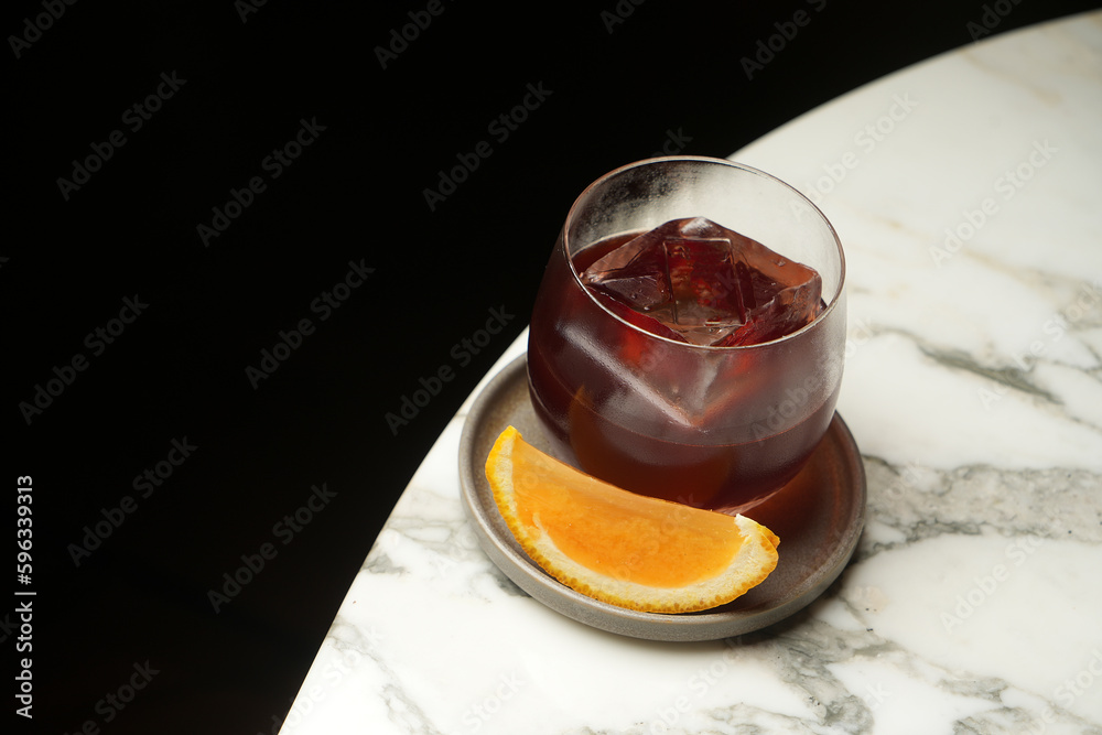 Glass of red cocktail with ice cube and orange slice Glass of red cocktail with ice cube and orange slice