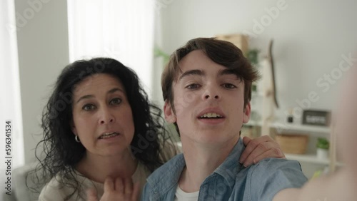 Camera point of view of teenager boy and mother live streaming at home. Woman and son talking to camera