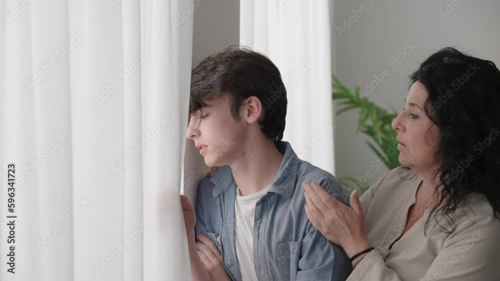 Woman comforting sad teenager boy. Mother talking and consoling son Woman comforting sad teenager boy. Mother talking and consoling son