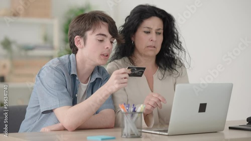 Mother and son shopping online together on laptop.