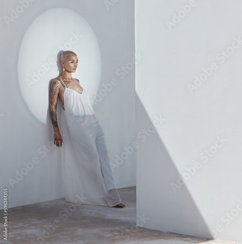 Beauty doesnt belong in the depths of your shadow. Shot of an attractive young woman posing in a white dress and leaning against a wall.