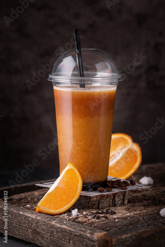 Foto fresh orange juice in takeaway plastic cup with fresh orange slices