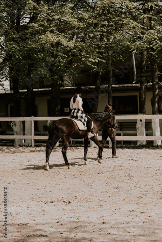 A woman instructor teaching girl how to ride a horse.  Female rider practicing on a horseback learning equestrian sport. Active lifestyle and leisure activity concep © Darius