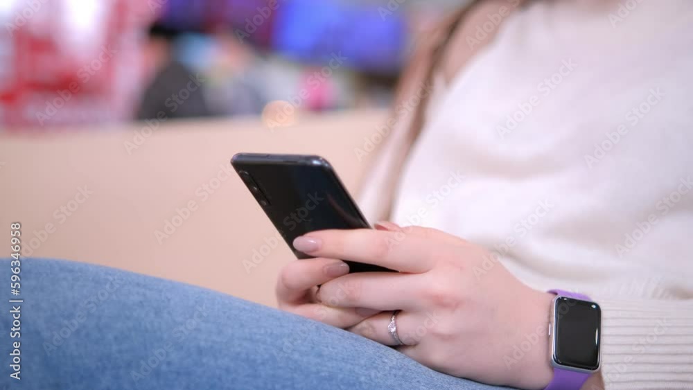 Woman using smartphone pressing finger, reading social media internet, typing text or shopping online. Mobile phone in two hands at mall