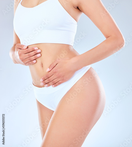 You are one routine away from a good mood. Shot of an unrecognizable woman posing with her hands around her belly against a grey background.