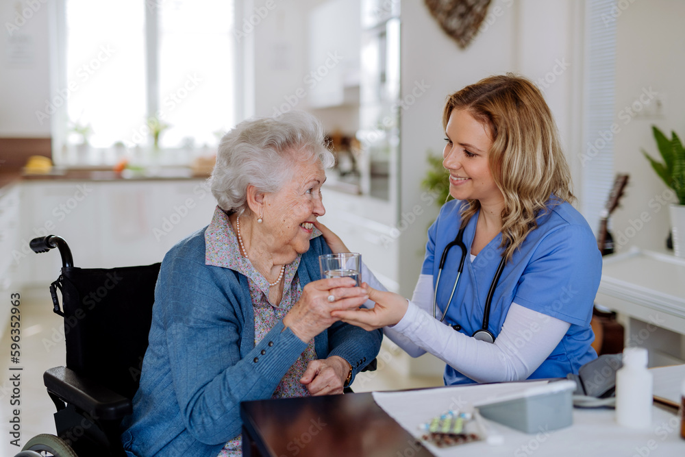 Fototapeta premium Nurse giving medicine to senior woman at her home.