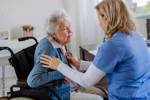 Nurse examining senior patient with stethoscope at her home.