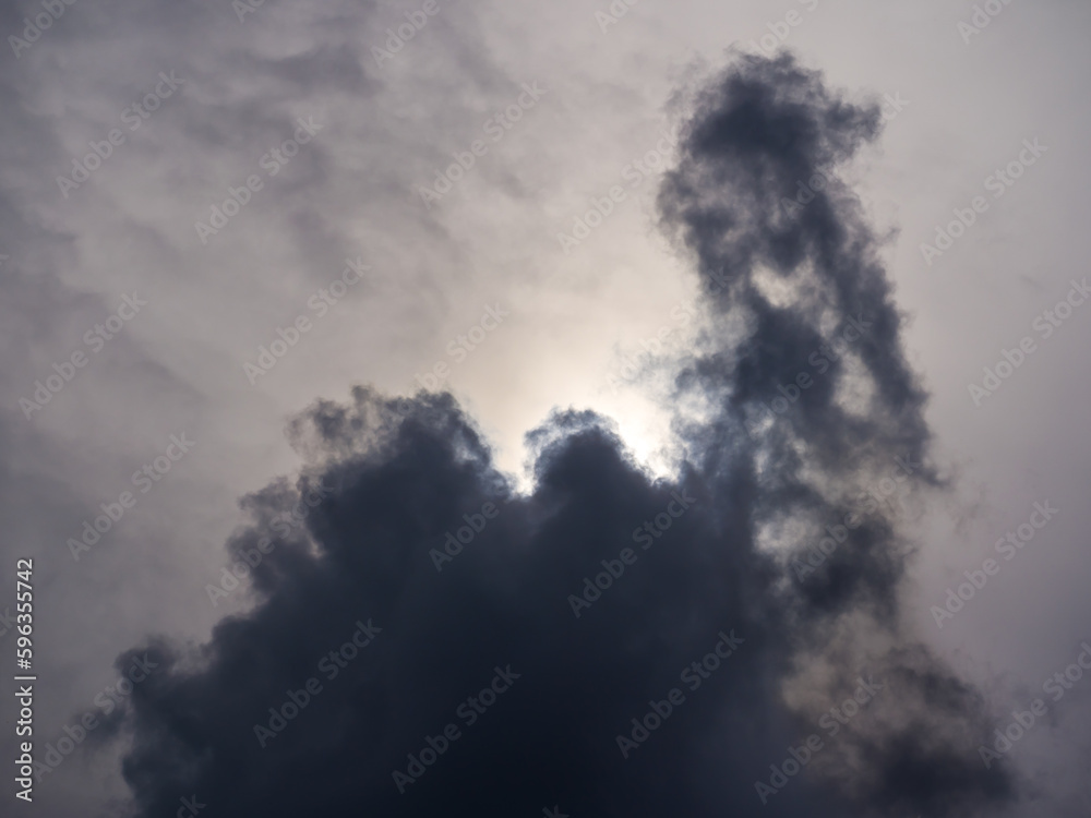 Sunlight behind ominous dark cloud in evening sky