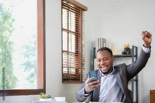 African American black man happy while reading company business results on smartphone and laptop. Business finance and technology concepts.