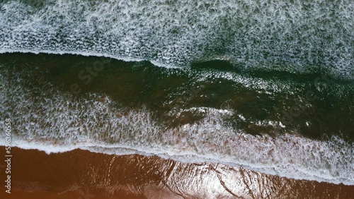 Drone view of beautiful seamless footage of Goa sea waves breaking on sandy coastline. Golden beach with deep blue ocean water and foamy waves arial shot