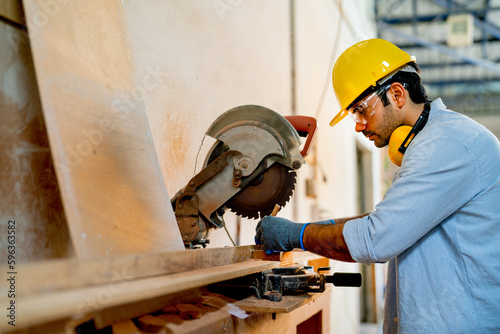 Side view of professional Caucasian carpenter man mark on timber and use electrical saw to work with timber in factory workplace. photo