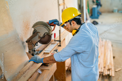 Top view of Caucasian carpenter man use electrical saw to work with timber in factory workplace. photo