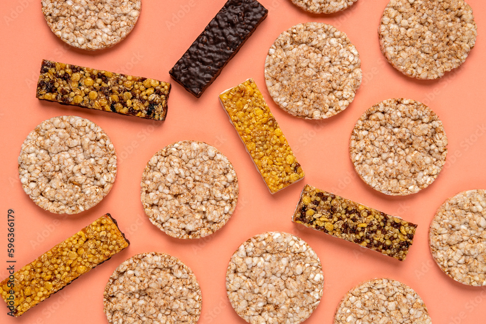 Top view of different kinds of fitness bars, crispbreads on the orange background. Texture of sport snacks Top view of different kinds of fitness bars, crispbreads on the orange background. Texture of sport snacks