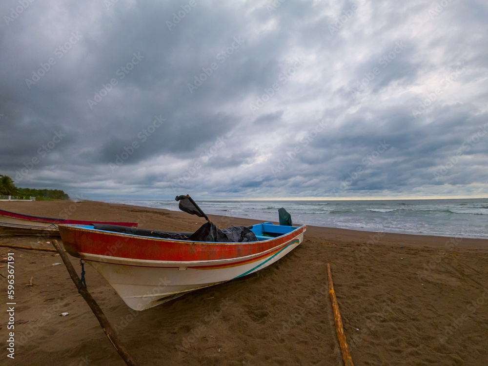 Traditional panga style boat marooned in the edge of the beach in Barra de Santiago, El Salvador Traditional panga style boat marooned in the edge of the beach in Barra de Santiago, El Salvador