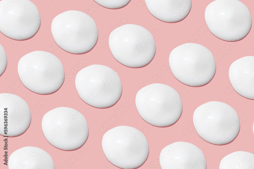 Lots of smears of cosmetic cream. Light, smooth surface. Texture of spreadable cream. Liquid creamy strokes. On a pink background. Cosmetic background, banner. Lots of smears of cosmetic cream. Light, smooth surface. Texture of spreadable cream. Liquid creamy strokes. On a pink background. Cosmetic background, banner.
