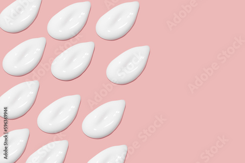 Lots of smears of cosmetic cream. Light, smooth surface. Texture of spreadable cream. Liquid creamy strokes. On a pink background. Cosmetic background, banner. © MM