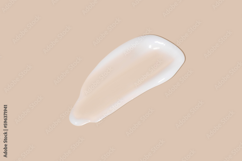 The flowing cream on a beige background. Smudged flowing smear of cosmetic cream.
