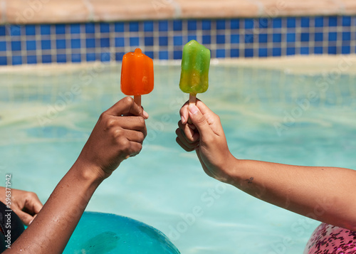 Foto Close up of friends holding ice lolly popsicles in the swimming pool, beat heat