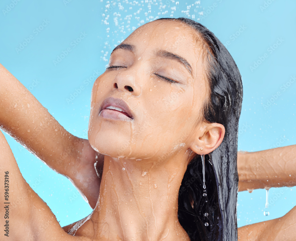 Naklejka premium Glow gang. Shot of an attractive young woman showering against a blue background.