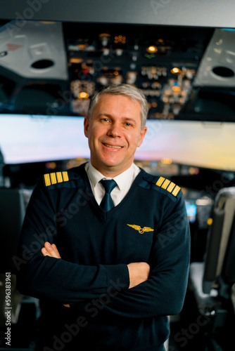 Portrait of smiling airplane captain in uniform preparing for flight in aero simulator cockpit
