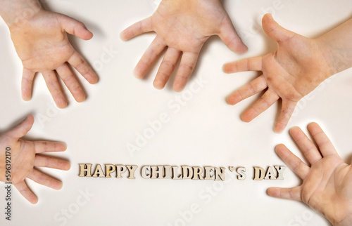 happy children's day words formed from eco wooden letters isolated with one or many kid child's hands from different parts of page.dirty small cute baby pre schooler kid palm.celebrate holiday june 1s