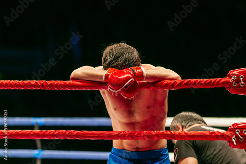 defeated fighter leaned on ropes ring after MMA fight