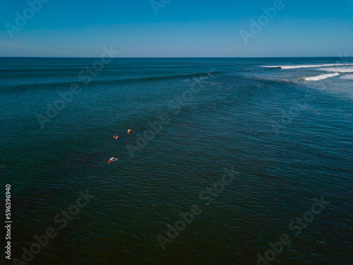 A pack of three surfers swim toward the tube waves crashing in Punta Roca, El Salvador