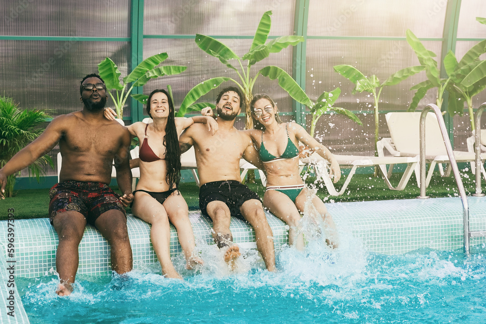 Summer vacation pool party: Group of friends having fun together inside luxury villa hotel - Multiracial people enjoy holiday weekend - Soft focus on center legs