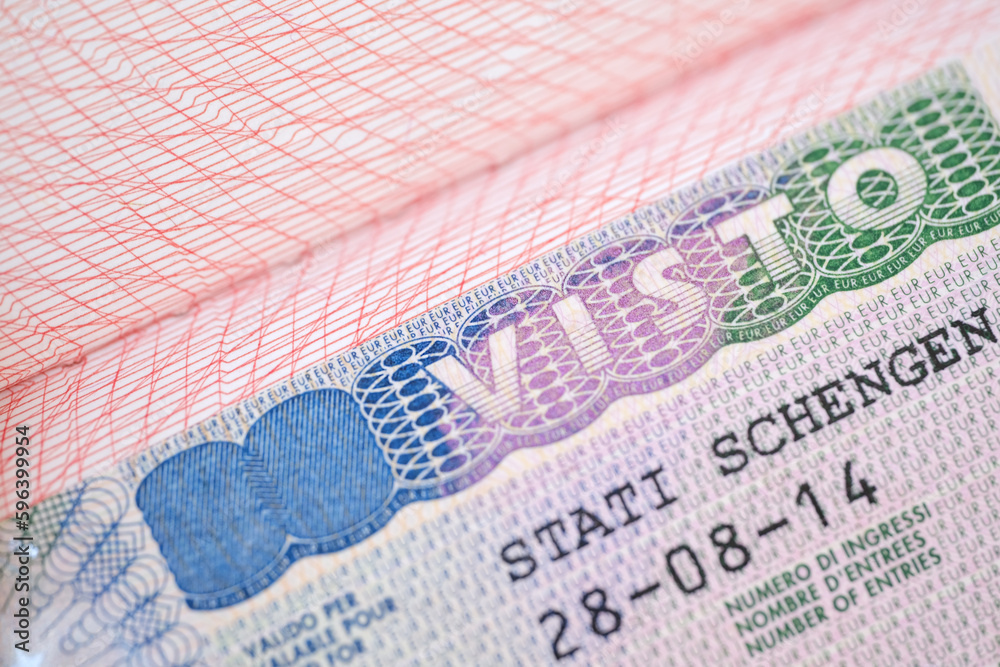 Fototapeta premium close-up part of page of document, foreign passport for travel with European visa, tourist schengen visa stamp with hologram with shallow depth of field, passport control at border, travel in Europe