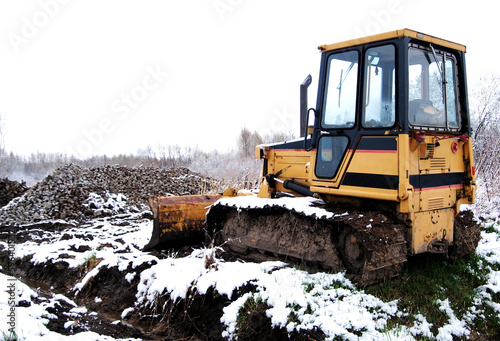 yellow crawler excavator on winter ground with snow
