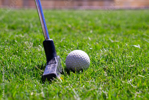 Mini golf putters with mini golf balls on grass. Mini golf club and balls. Selective focus.