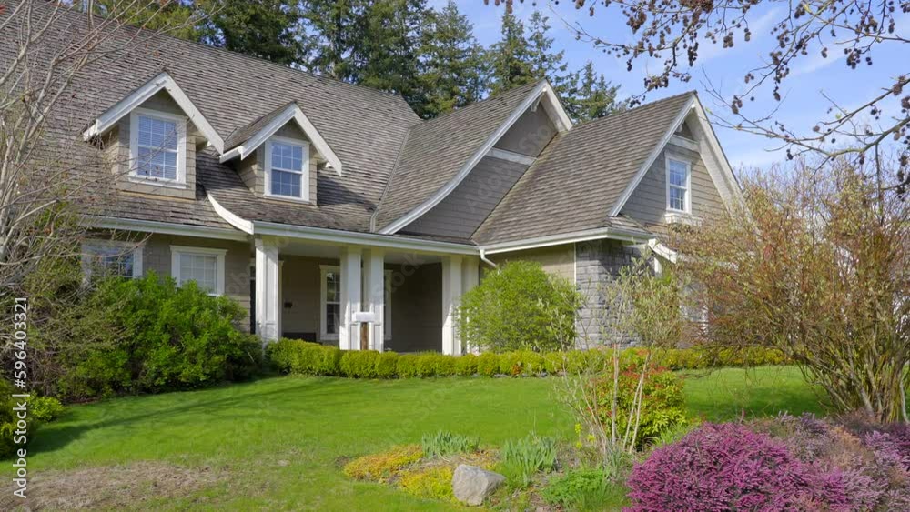 Establishing shot of two story stucco luxury house with garage door, big tree and nice spring blossom landscape in Vancouver, Canada, North America. Day time on Apr 2023. ProRes 422 HQ.