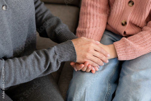 European millennial mother holding hands calms sad teenage girl in living room interior, cropped, top view