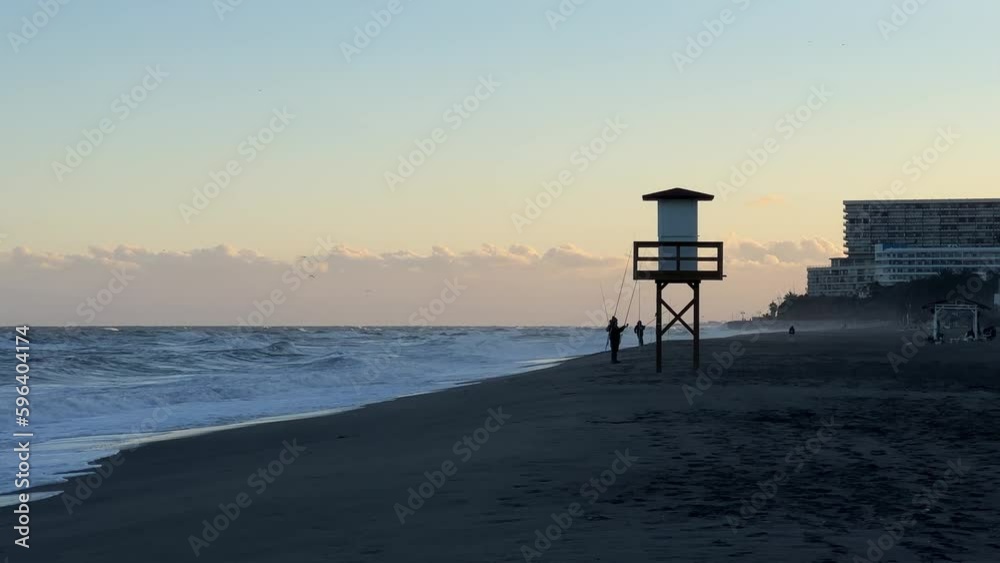 Torremolinos beach, rescue tower and men fishing during the storm in the evening Torremolinos beach, rescue tower and men fishing during the storm in the evening