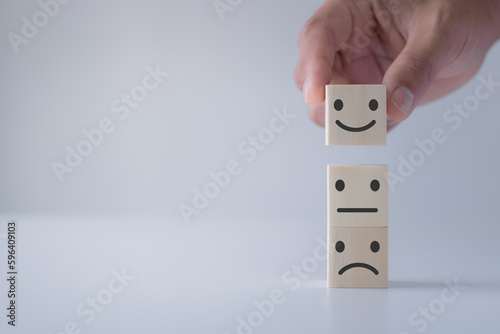 Customer satisfaction survey concept. smiling face on sad face. Wooden cube block stacking with icon face. Customer showing rating The best excellent business services rating customer experience.