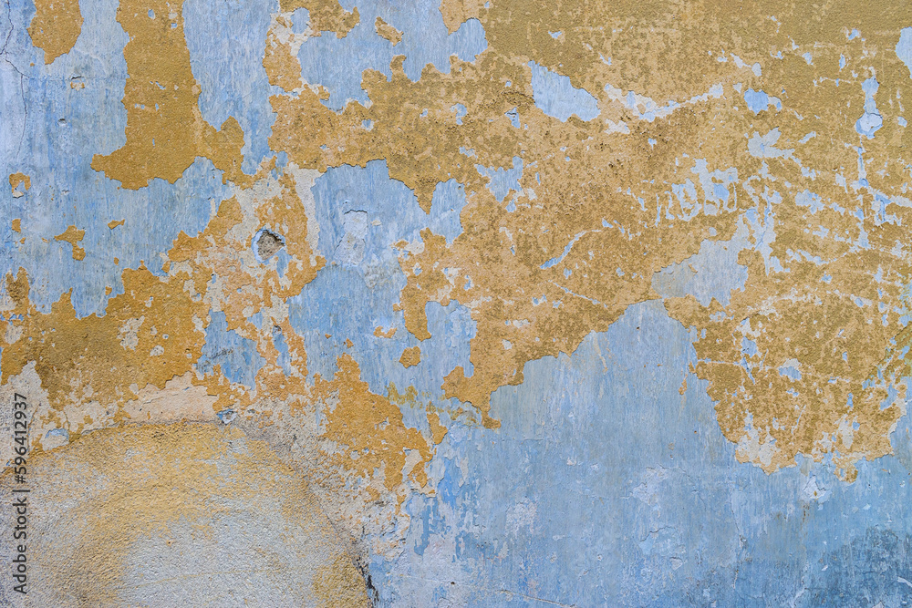 The texture of old, cracked, peeling walls. The background is blue and yellow walls