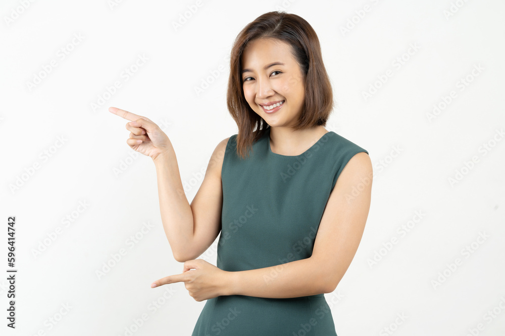 Young smiling Asian woman pointing finger sideways to copy space in pink color background. Young smiling Asian woman pointing finger sideways to copy space in pink color background.