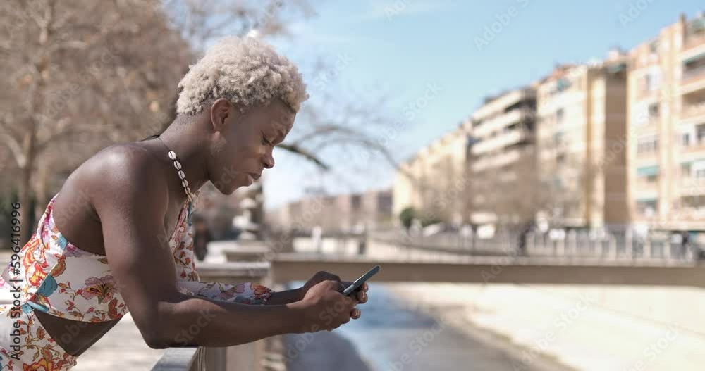 Annoyed black queer man messaging on smartphone on street Annoyed black queer man messaging on smartphone on street
