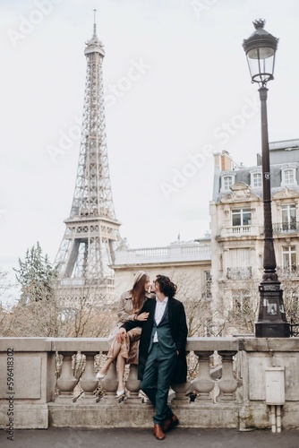 A couple in love walks along the streets of Paris, a guy in a coat and a suit, a girl in a dress with a beret and a trench coat in autumn © Максим Екстрактер