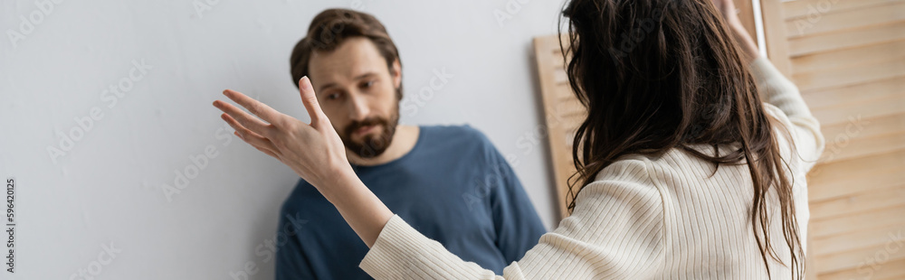 Brunette woman quarrelling with sad blurred boyfriend at home, banner. Brunette woman quarrelling with sad blurred boyfriend at home, banner.