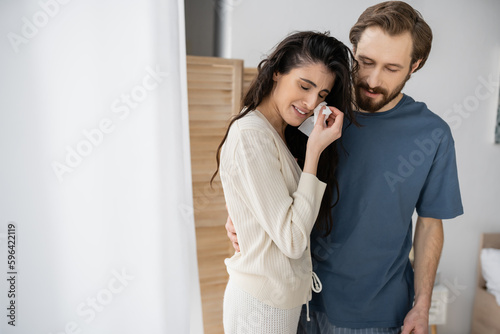 Bearded man hugging and calming crying girlfriend at home.