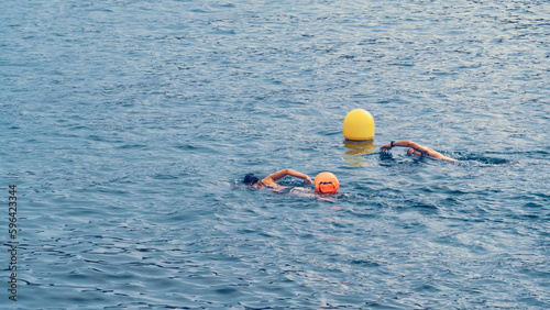 A pair of athletes swimming in open water with front crawl. They represent a healthy lifestyle and the willpower of sport in this inspiring triathlon concept